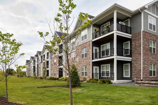 Apartment building with balconies and trees in front.