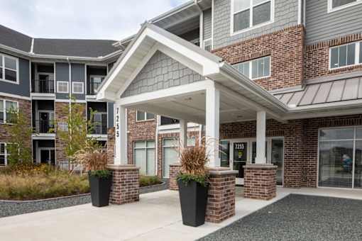 A building with a covered walkway and potted plants on either side.