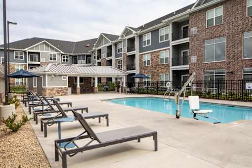 A pool area with sun loungers and a slide in front of apartment buildings.