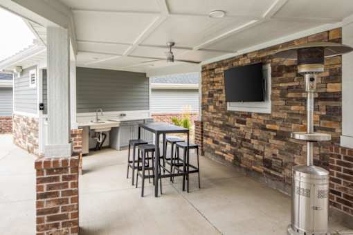 A patio with a table and chairs and a brick wall.