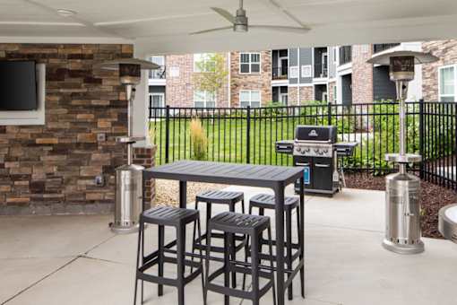 A patio with a table and chairs and a grill.