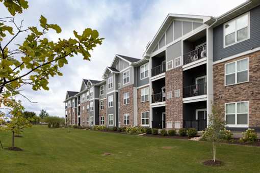 Apartment building with balconies and a green lawn in front.