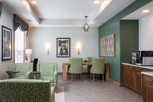 A living room with a green couch and a dining table with chairs.at The Edison at Rice Creek I and II, Shoreview