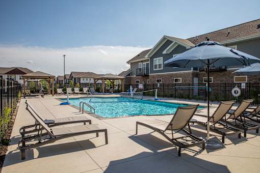 A pool surrounded by chairs and umbrellas at The Edison at Spirit, Minnesota