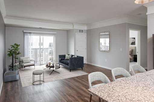 A living room with a grey couch, a white chair, and a round table at The Edison at Woodbury, Woodbury, 55129