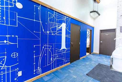 A hallway with a blue wall covered in architectural drawings.