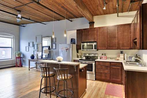 A kitchen with wooden cabinets and a large island with bar stools.