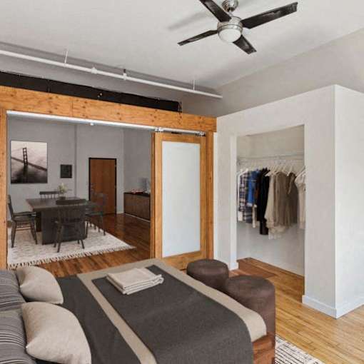 A bedroom with a bed, a chair, and a ceiling fan.