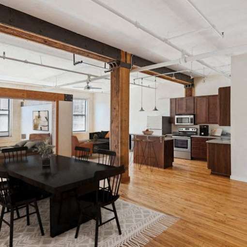 A modern kitchen with wooden floors and a dining table with chairs.
