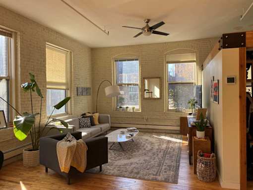 A living room with a grey couch and a rug.