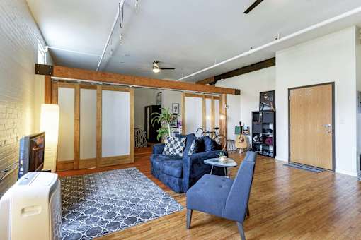 A living room with a blue couch and a grey rug.