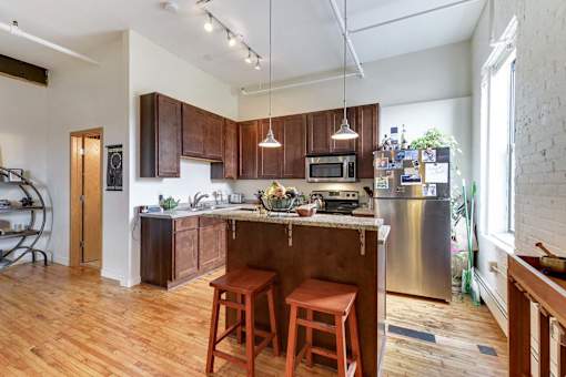 A kitchen with wooden floors and a large island with a bar stool.