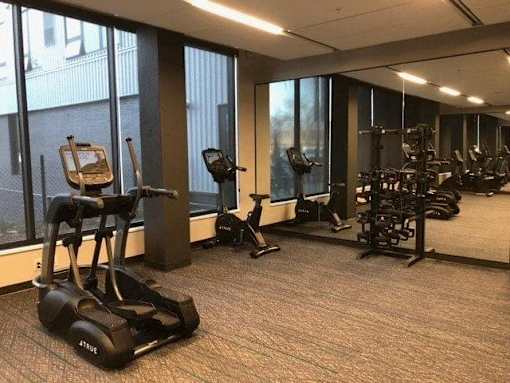 A gym with treadmills, elliptical machines, and other exercise equipment at The Redwell Apartments, Minneapolis
