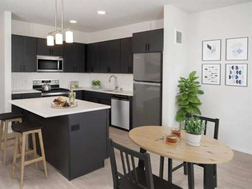 A modern kitchen with a dining table and chairs at The Redwell Apartments, Minneapolis, 55401