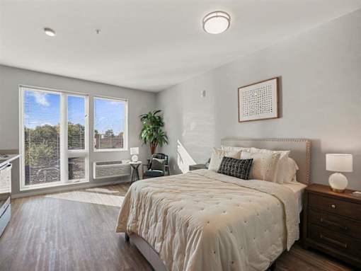 A bedroom with a large bed and a view of the outdoors through the sliding glass doors.