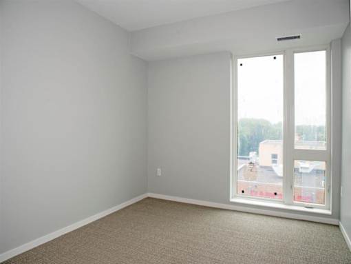 A room with a carpeted floor and a window overlooking a cityscape.