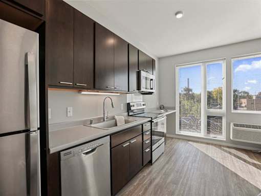A modern kitchen with dark wood cabinets and stainless steel appliances.