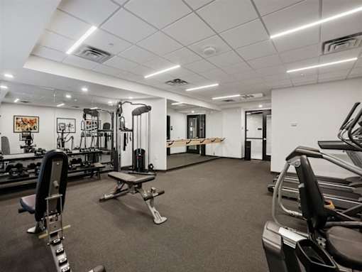 A gym with a variety of equipment including a treadmill, weights, and a bench.