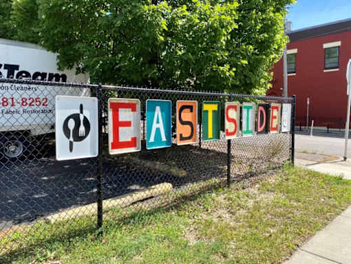 A sign that says Eastside is hanging on a fence.
