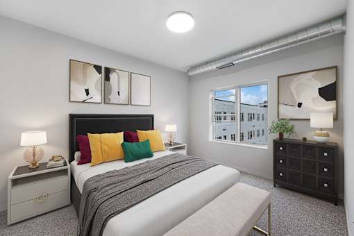 A bedroom with a bed, nightstand, and a window with a view of a building at Soul Apartments, Minnesota 55107