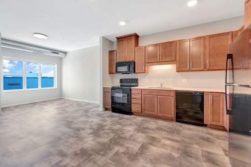 A kitchen with wooden cabinets and black appliances at Soul Apartments, St. Paul, MN