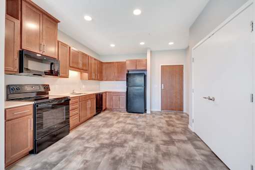A kitchen with wooden cabinets and a black refrigerator at Soul Apartments, Minnesota