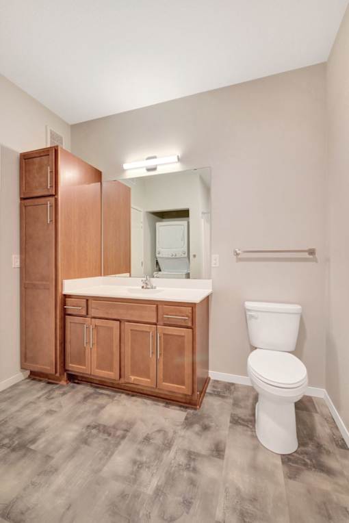 A bathroom with a toilet, sink, and wooden cabinets at Soul Apartments, St. Paul, MN