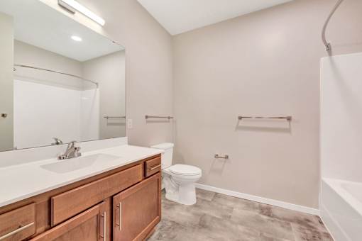 A bathroom with a white sink, toilet, and a mirror at Soul Apartments, St. Paul, MN 55107