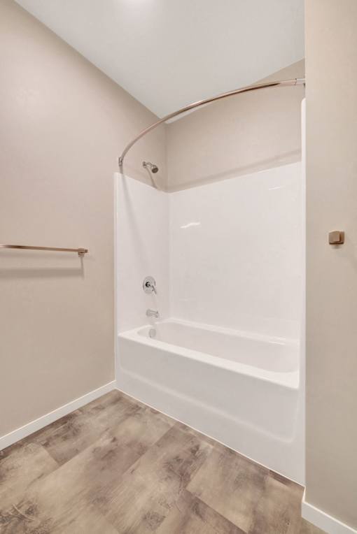 A white bathtub in a bathroom with a wooden floor at Soul Apartments, Minnesota