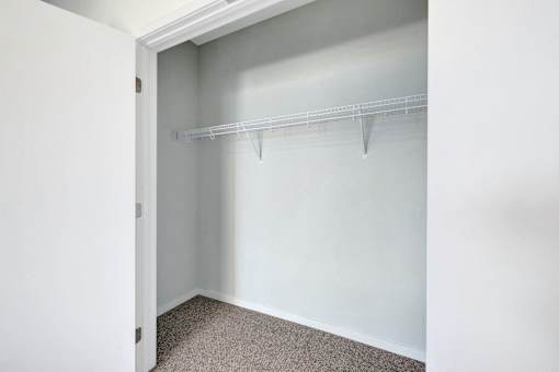 A white closet with a shelf and carpeted floor at Soul Apartments, St. Paul, MN