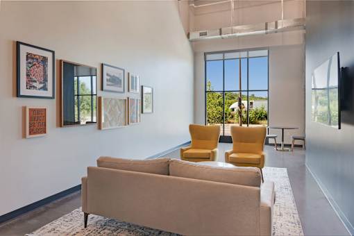 A living room with a tan couch and yellow chairs at Soul Apartments, St. Paul