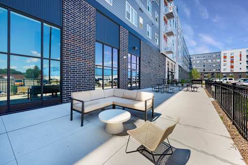 A patio area with a white couch, a white table, and a black railing at Soul Apartments, St. Paul, Minnesota