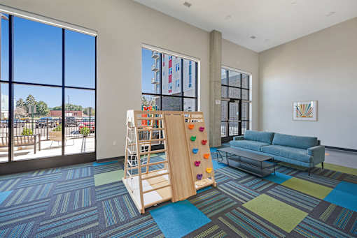 A room with a blue couch and a wooden climbing structure at Soul Apartments, St. Paul, MN 55107