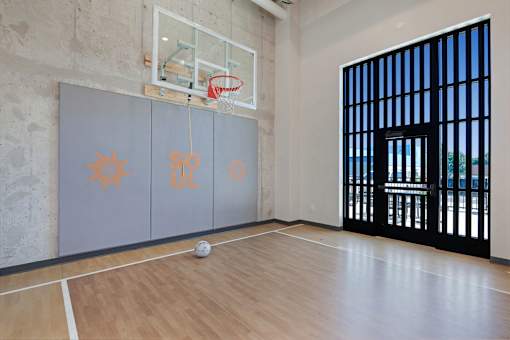 A basketball court with a ball on the floor and a basketball hoop with a net at Soul Apartments, St. Paul