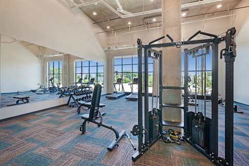 A gym with a row of exercise machines and a weight rack at Soul Apartments, St. Paul, 55107