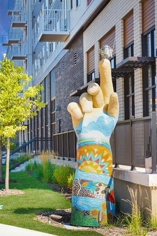 A large hand sculpture is in front of a building at Soul Apartments, Minnesota 55107