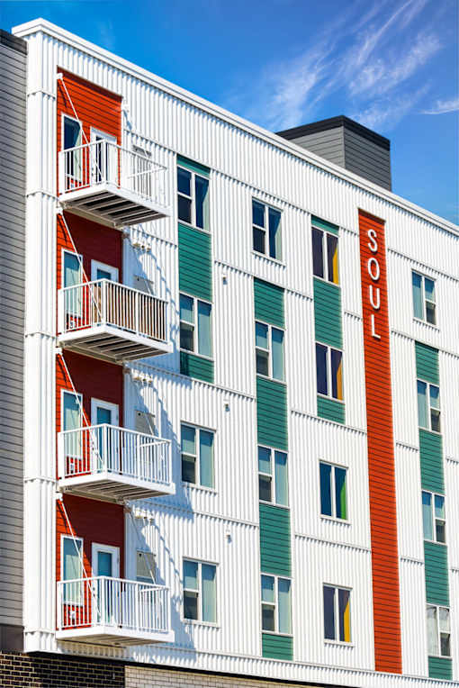 A white building with balconies and a red door at Soul Apartments, St. Paul, MN