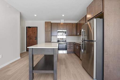 A modern kitchen with a stainless steel refrigerator and wooden cabinets.at Croft at Rosecott, Rosemount, MN