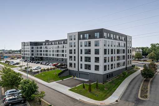 A modern multi-story building with a parking lot in front.