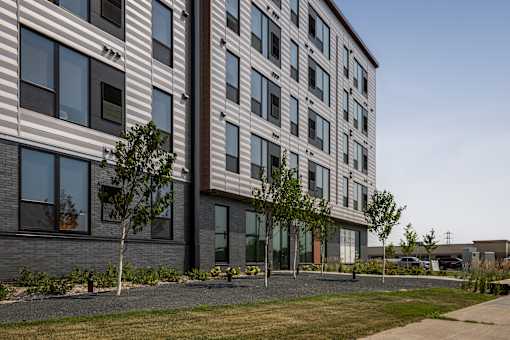 A modern building with a striped facade and trees in front.
