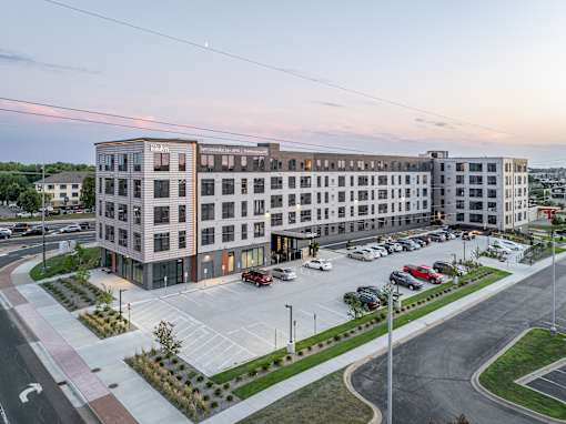 A large, modern building with a parking lot in front of it.
