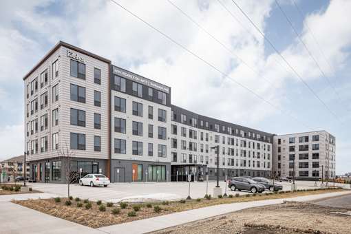 A modern apartment building with cars parked in front.