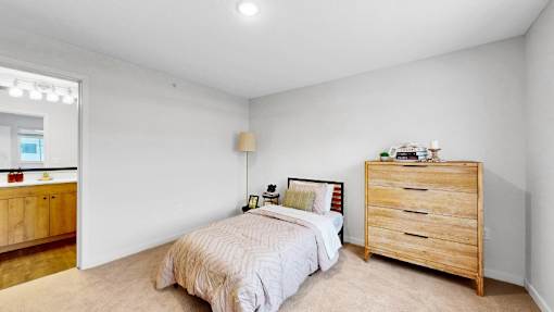 A bedroom with a bed, nightstand, and dresser.