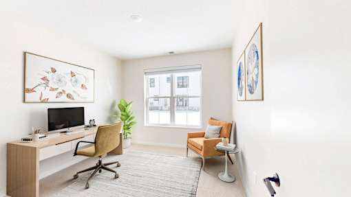 A room with a desk, chair, and a painting on the wall.