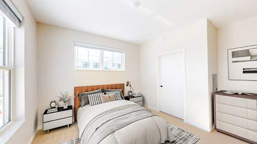 A bedroom with a bed, nightstand, and window.