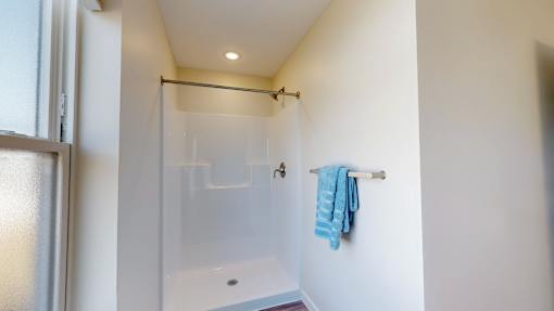 A blue towel is hanging on a white wall next to a glass shower door.