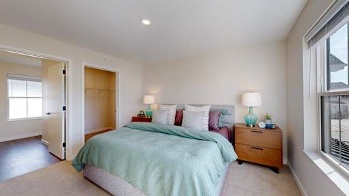 A bedroom with a bed, nightstand, and window.