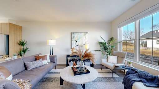 A modern living room with a grey sofa, a coffee table, and a large window.