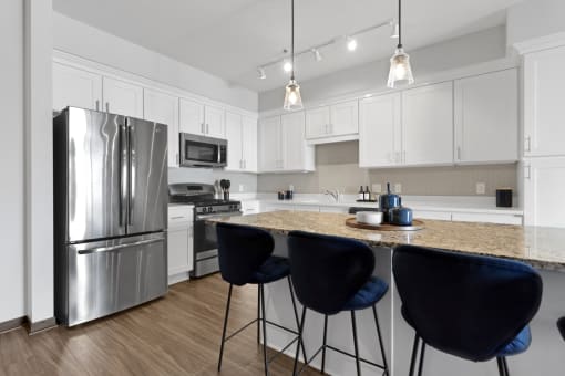 a kitchen with stainless steel appliances and an island with blue chairs