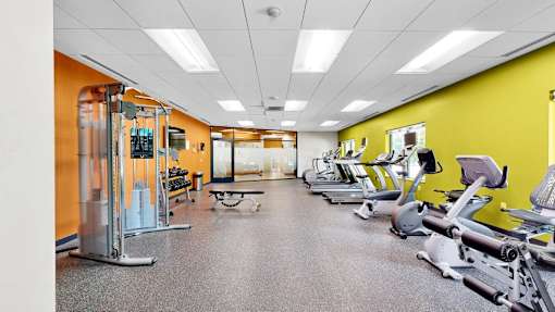 A gym with a variety of equipment including treadmills, weights, and exercise machines.